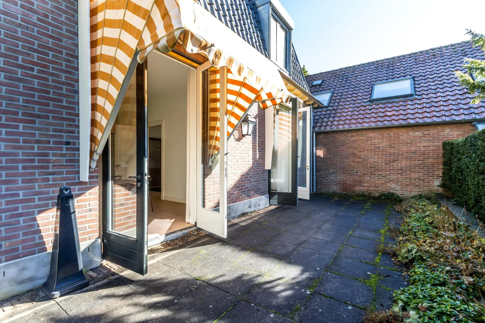 Terras met openslaande deuren en gestreepte zonneschermen aan de Langbroekerdijk A.